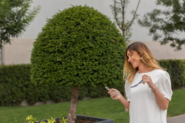 Aantrekkelijke jonge vrouw texting in het Park — Stockfoto