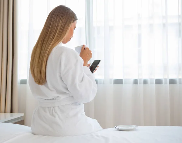 Bella donna seduta sul letto a godersi il caffè del mattino — Foto Stock