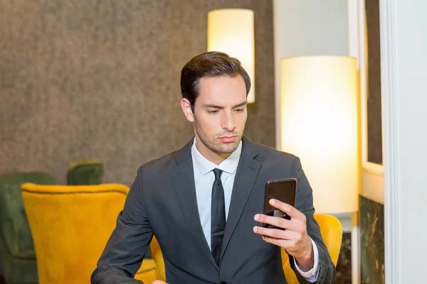 Hombre joven atractivo mirando en el teléfono celular —  Fotos de Stock