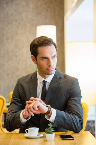 Attractive young  man looking   holding his wristwatch — Stock Photo, Image