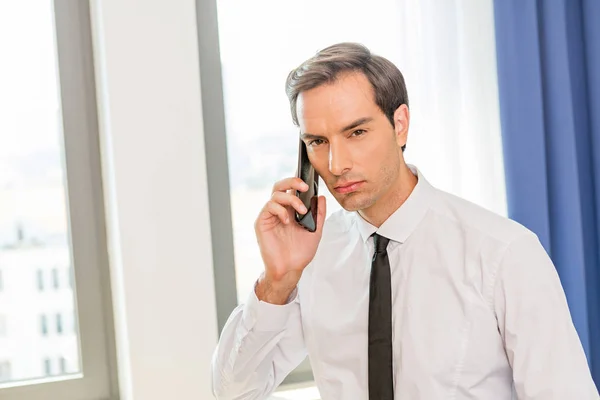 Бизнесмен разговаривает по мобильному телефону в номере отеля — стоковое фото