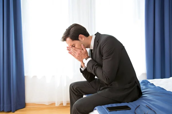 Frustrated businessman sitting on the hotel bed — Stock Photo, Image