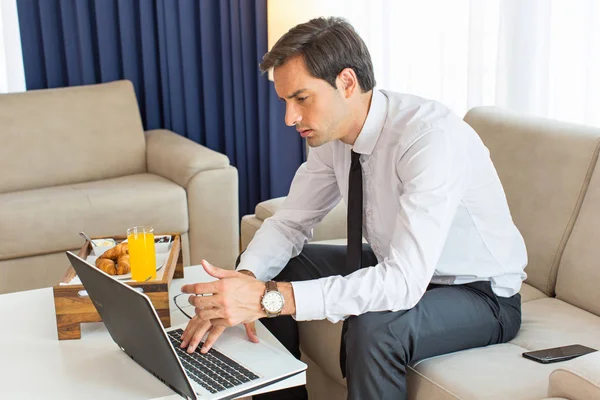 Joven empresario guapo trabajando en el cuaderno en un hotel ro —  Fotos de Stock