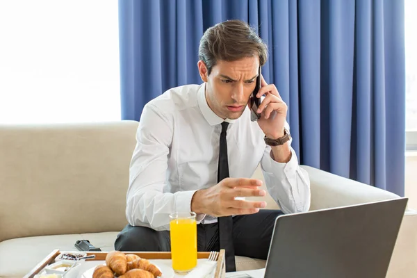 Businessman talking on the mobile phone in his hotel room — Stock Photo, Image