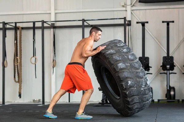 Fisiculturista flipping pneu no ginásio — Fotografia de Stock