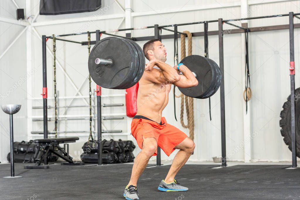 Bare chested man weightlifting barbell in gym