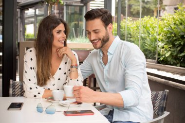 Bahçe restoranında kahve içen çekici genç bir çift.