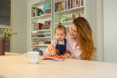 Anne, bebeğine kitap okuyor.