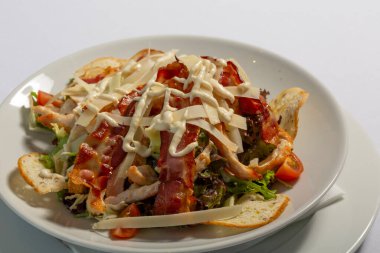 Beyaz tabakta servis edilen domuz pastırmalı Sezar salatası.