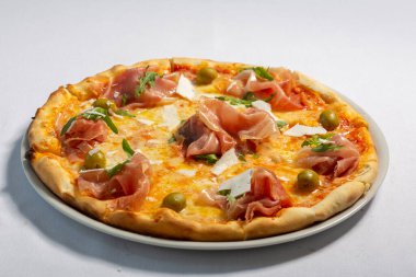 Prosciutto pizzası beyaz tabakta servis edilir.