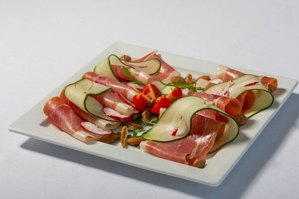 Appetizer prosciutto served on a white plate