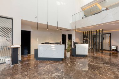 Mermer zemin, resepsiyon tezgahı olan lüks bir otel lobisi.