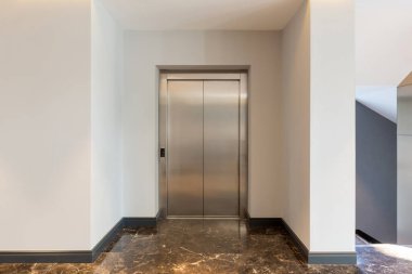 Asansör kapısı olan otel lobisi.