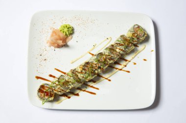 Beyaz bir tabakta servis edilen volkanik suşi rulosu.