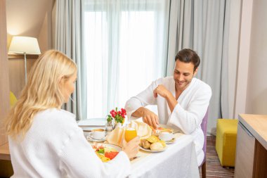 Mutlu çift otel odasında kahvaltı yapıyor.