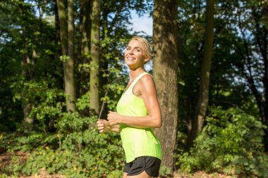 Yakışıklı kadın doğada koşuyor.