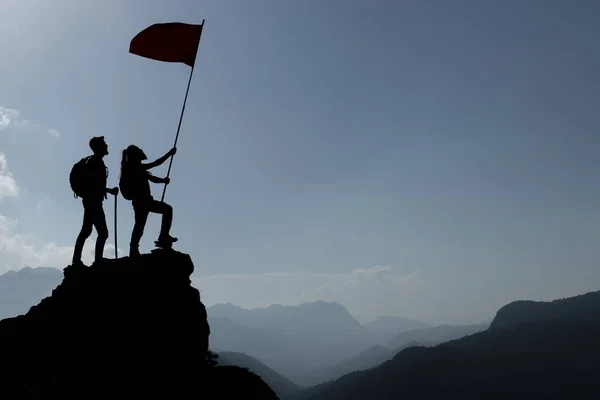 friend holding flag on top mountain. Conception of winner, success and leadership