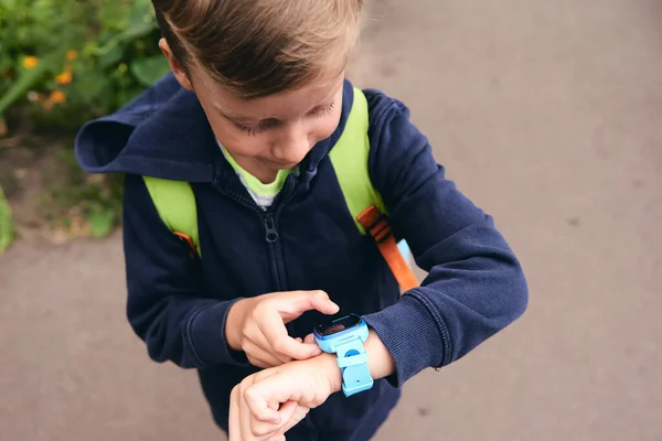 Wearable kids baby smart watch calls mom and location tracking with touch screen and voice service, blue multicolored electronic gadget with rubber wristband for children. Close up boy with copy space. Time clock for school.