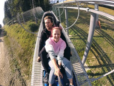 Yaz kızakçıları bir dağda birçok virajla rodelbahn koşar. Yazın ve sonbaharda, güzel manzaralarda alp altlığı. Seyahat eden genç çiftin hızlı yolculuğu..