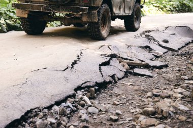 Sert adam için bir yol. Araba yağmurdan sonra toprak yolda yarışıyor. Tekerlek, kaput, ayna ve kapı çamurla kaplı. Sonbahar doğası kırsal kesimde ıslak çamurlu bir araba parçası..