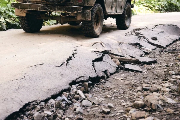 Sert adam için bir yol. Araba yağmurdan sonra toprak yolda yarışıyor. Tekerlek, kaput, ayna ve kapı çamurla kaplı. Sonbahar doğası kırsal kesimde ıslak çamurlu bir araba parçası..