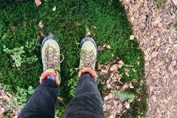 Botas de senderismo en acción al aire libre. Vista superior de la bota en el camino. Piernas de cerca en pantalones vaqueros y zapatos deportivos de trekking en los srones rocosos de la cascada del río Montaña — Foto de Stock