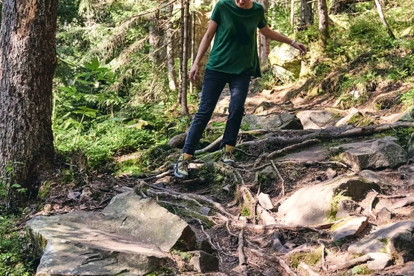 Közelkép Lábak A sport túracipő zöld fű és sziklás kövek moha hegyi őszi erdőben. A nő sportos ruhákba és hátizsákba mászik. Túracipő szabadtéri akcióban. A csizma tetejére — Stock Fotó
