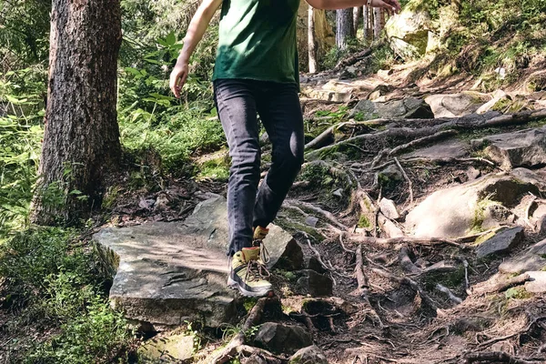 Közelkép Lábak A sport túracipő zöld fű és sziklás kövek moha hegyi őszi erdőben. A nő sportos ruhákba és hátizsákba mászik. Túracipő szabadtéri akcióban. A csizma tetejére — Stock Fotó