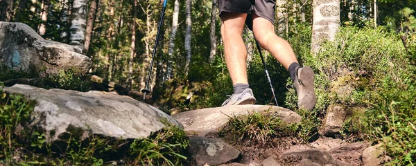 Man climbs in sneakers in outdoor action. Top View of hiking Boot on the trail. Close-up Legs In Jeans And sport trekking shoes on rocky stones of Mountain forest — Stock Photo, Image