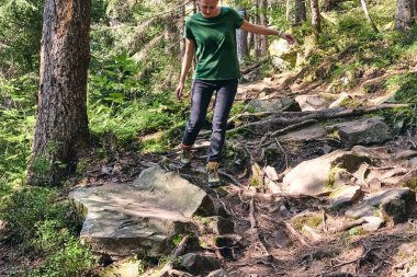 Adam dağ buhar nehrine tırmanıyor. Spor kıyafetler ve sırt çantası. Yürüyüş botları dışarıda. Top View of Boot yolda. Spor yürüyüş ayakkabılarıyla Dağ nehri şelalesinin kayalık taşlarında.