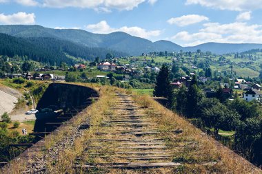 Eski köprünün panorama manzarası. Yeşil dağ ormanı tepesi yakınlarında eski demiryolu rayları olan bir viyadük. Locat seyahat kavramı.
