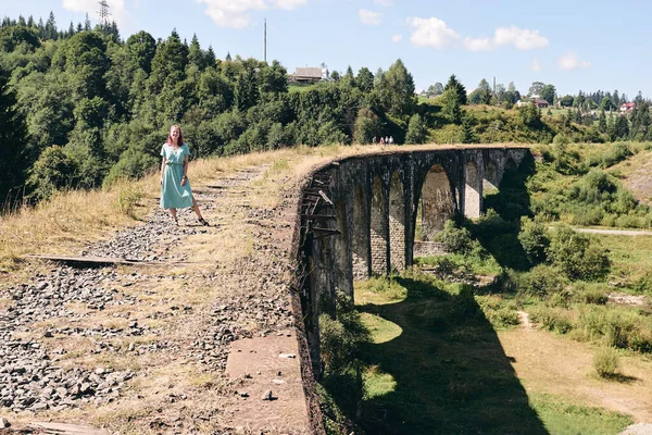 年轻的旅游姑娘走在古老的桥上 一个女人坐在高架桥上 上面有旧铁轨 位于Vorokhta山区度假村的老铁路高架桥 乌克兰 喀尔巴阡山脉 地点旅行概念 — 图库照片