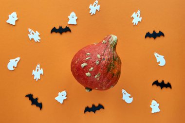 Sonbahar kompozisyonu. Turuncu arka planda yarasa ve hayalet desenli bir balkabağı. Şablon sonbahar, sonbahar, cadılar bayramı, hasat günü konsepti. Düz konum, üst görünüm, alan arkaplanı kopyala.