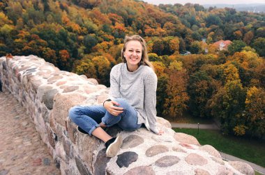 Genç kız sonbahar ormanında yürüyüş yapıyor. Kuru sarı, kırmızı yaprakları ve renkli ağaçları olan güzel bir park..