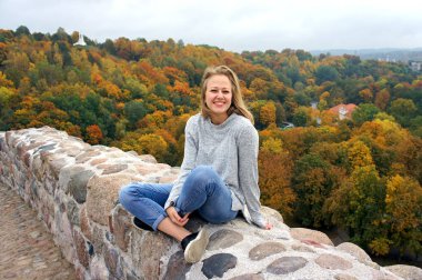 Genç kız sonbahar ormanında yürüyüş yapıyor. Kuru sarı, kırmızı yaprakları ve renkli ağaçları olan güzel bir park..