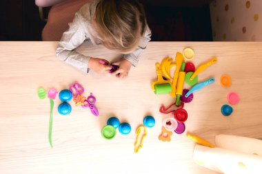 3 yıl kız yaratıcı sanatlar. Çocuk elleri renkli kil plastikinle oynuyor. Kendini tecrit Covid-19, online eğitim, evde eğitim. Küçük kız evde çalışıyor, evde öğreniyor..