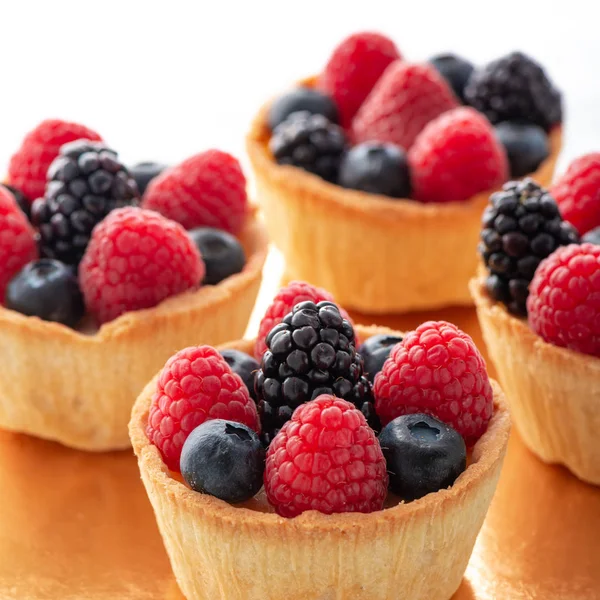 Tartlet cakes - raspberries, blackberries and blueberries white background