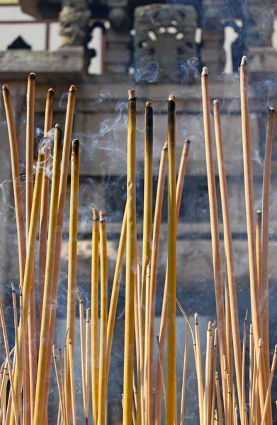 Incense stick burning, smoky and fuming, blur ancient carving sand stone wall on background