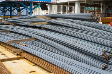 İnşaatta binanın önündeki beton zeminde pasla kaplanmış yeni bir çelik çubuk yığını.