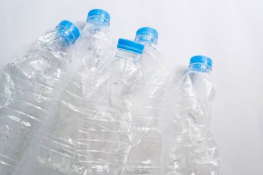 Beyaz zemin üzerinde mavi kapaklı deforme olmuş temiz plastik su şişeleri