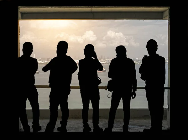 Group of black shadow of men standing in line on bacony looking at sea and city view, silhouette photo