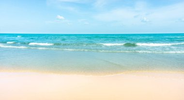 Temiz beyaz kumsal altın sarısı kumsal ve açık mavi gökyüzünün altında güneşli bir günde mavi denizden gelen küçük dalgalar.