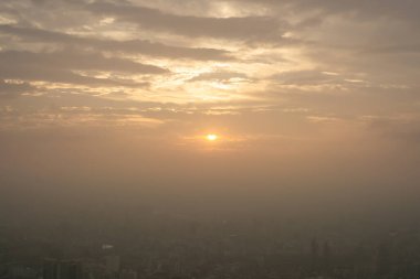 Binanın üstünde güzel bir gün batımı sahnesi, turuncu ışık ve şehrin her yerinde sis var. 