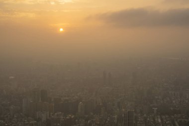 Binanın üstünde güzel bir gün batımı sahnesi, turuncu ışık ve şehrin her yerinde sis var. 