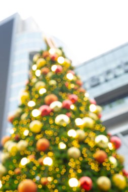 Renkli bokeh fotoğrafı, kırmızı, altın, sarı ve beyaz ışıklarla süslenmiş Noel ağacı süslemesi çam ağacının yeşil yaprakları, Mutlu Noeller ve mutlu yıllar için dekorasyon sezonu. 