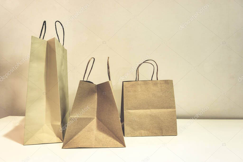 The brown color paper shopping bags on the table and the light brown wallpaper