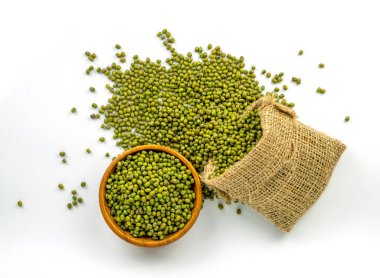 Kahverengi çuvalda yeşil fasulye olarak bilinen bir yığın Mung fasulyesi ve ahşap kase, beyaz arka planda üst manzara.