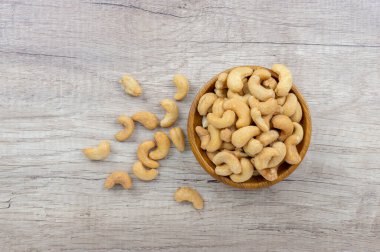 Tahta kasede tuzla kavrulmuş kaju fıstığı tohumu ve ahşap masaya dökülmüş.