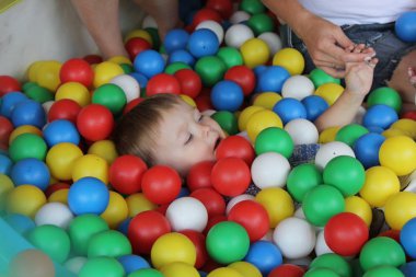 Mothers with babies plays in swimming pool for fun and boy digging in the colored plastic balls.