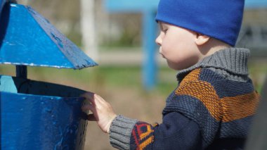 Meraklı küçük çocuk yaşlı mavi çöp Kutusu'na görünüyor